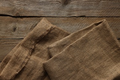 Burlap fabric on wooden table, top view