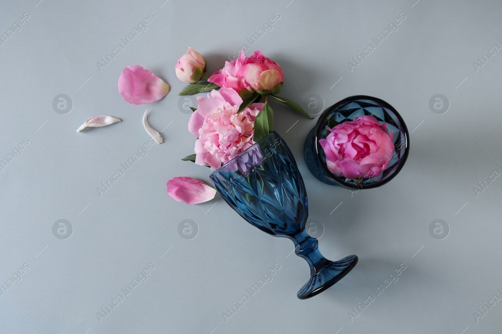 Photo of Flat lay composition with wineglasses and beautiful pink peonies on grey background