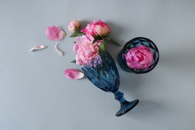 Photo of Flat lay composition with wineglasses and beautiful pink peonies on grey background