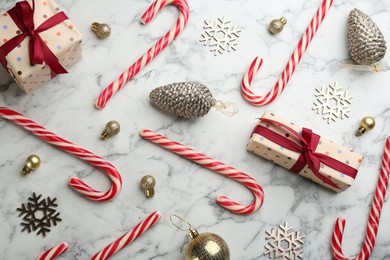 Flat lay composition with candy canes and Christmas decor on white marble table