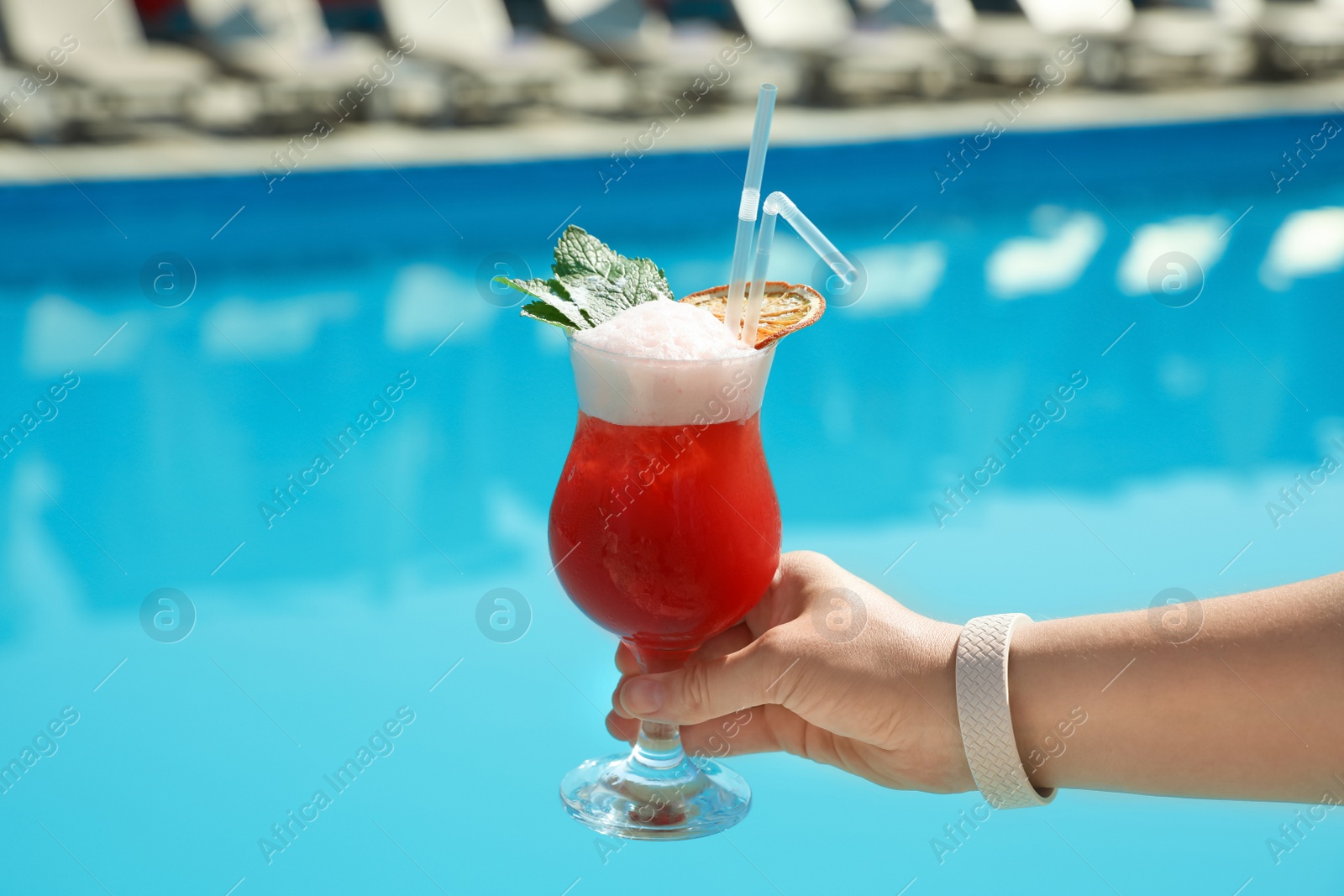 Photo of Woman with refreshing cocktail near swimming pool outdoors, closeup