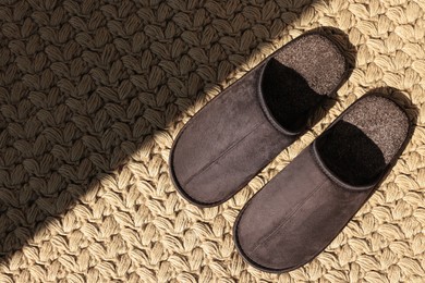 Photo of Pair of brown slippers on carpet, top view. Space for text