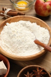 Photo of Bowl with flour and ingredients on wooden table, closeup. Cooking yeast cake