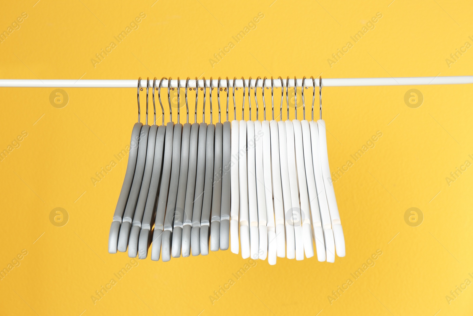 Photo of Metal rack with clothes hangers on color background