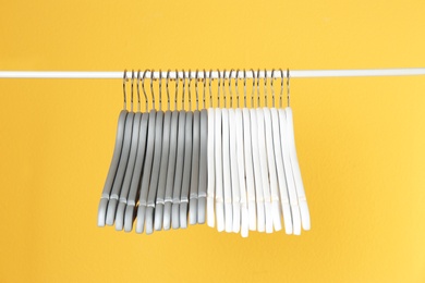 Metal rack with clothes hangers on color background