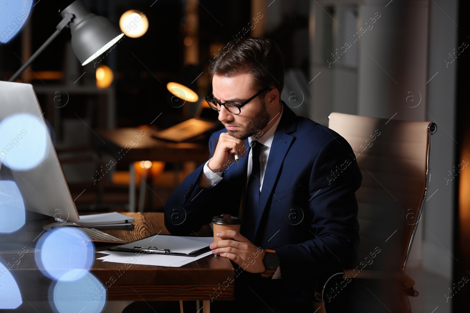 Photo of Concentrated young businessman working in office alone at night