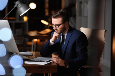 Photo of Concentrated young businessman working in office alone at night