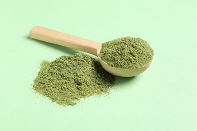 Photo of Wheat grass powder and spoon on green table