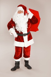 Photo of Authentic Santa Claus with bag full of gifts on grey background