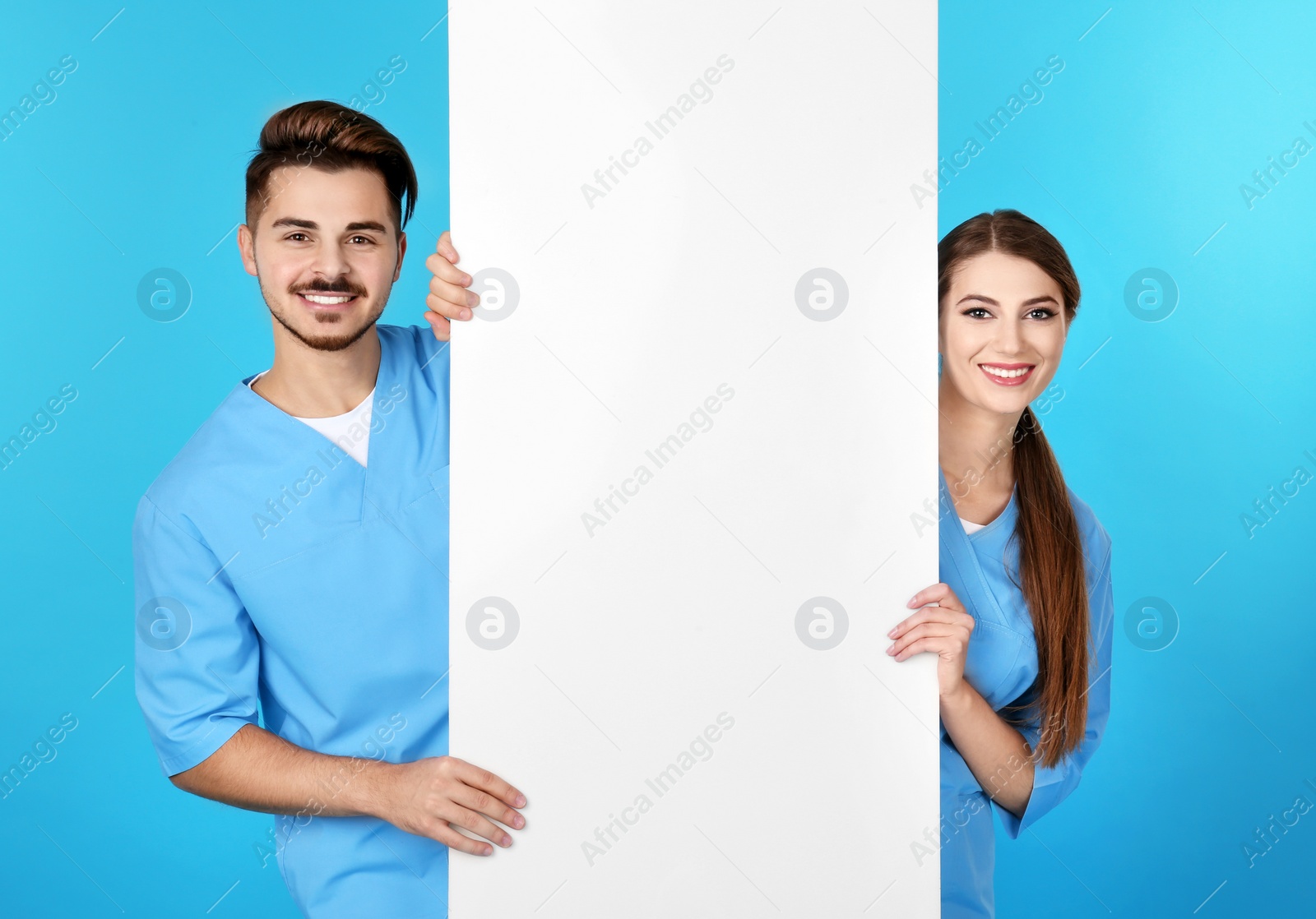 Photo of Medical students with blank poster on color background. Space for text