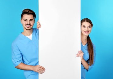 Photo of Medical students with blank poster on color background. Space for text