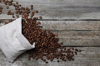 Photo of Bag with roasted coffee beans on wooden table, flat lay. Space for text