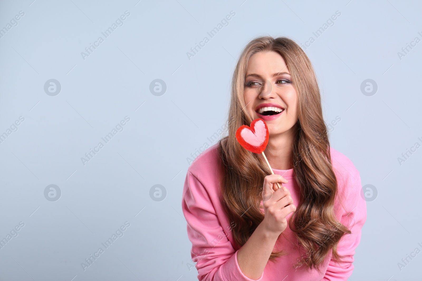Photo of Portrait of young woman with long beautiful hair and lollipop on color background