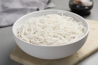 Bowl with cooked rice noodles on light grey table, closeup