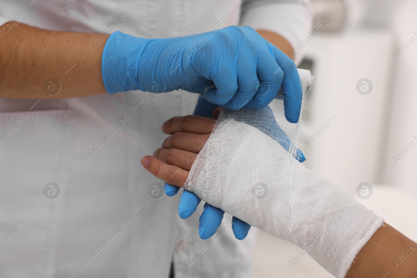 Photo of Doctor bandaging patient's burned hand indoors, closeup