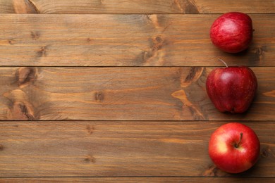 Photo of Fresh red apples on wooden table, flat lay. Space for text