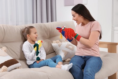Emotional mother and daughter playing with funny sock puppets together at home