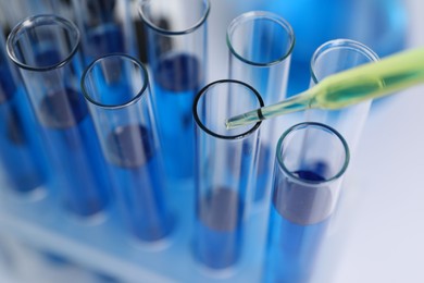 Photo of Laboratory analysis. Dripping liquid into test tubes on white table, closeup