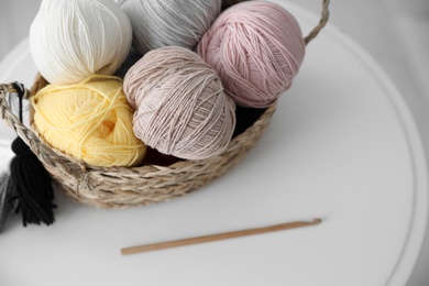 Photo of Clews in wicker basket and crochet on table indoors, above view. Engaging in hobby