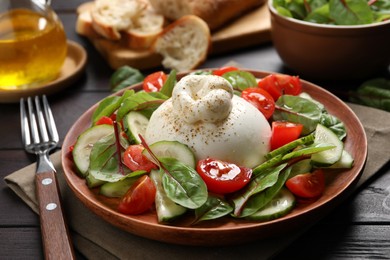 Photo of Delicious burrata salad served on wooden table