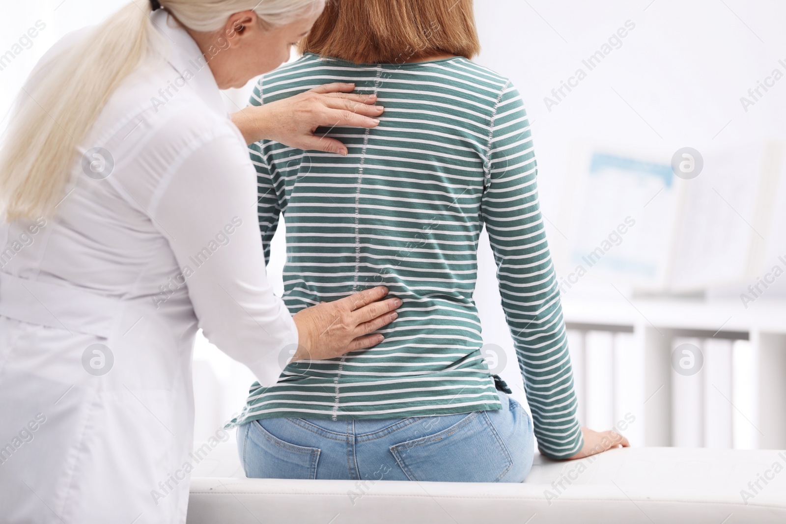 Photo of Chiropractor examining patient with back pain in clinic