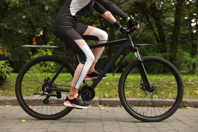 Photo of Young woman riding bicycle on road outdoors, closeup