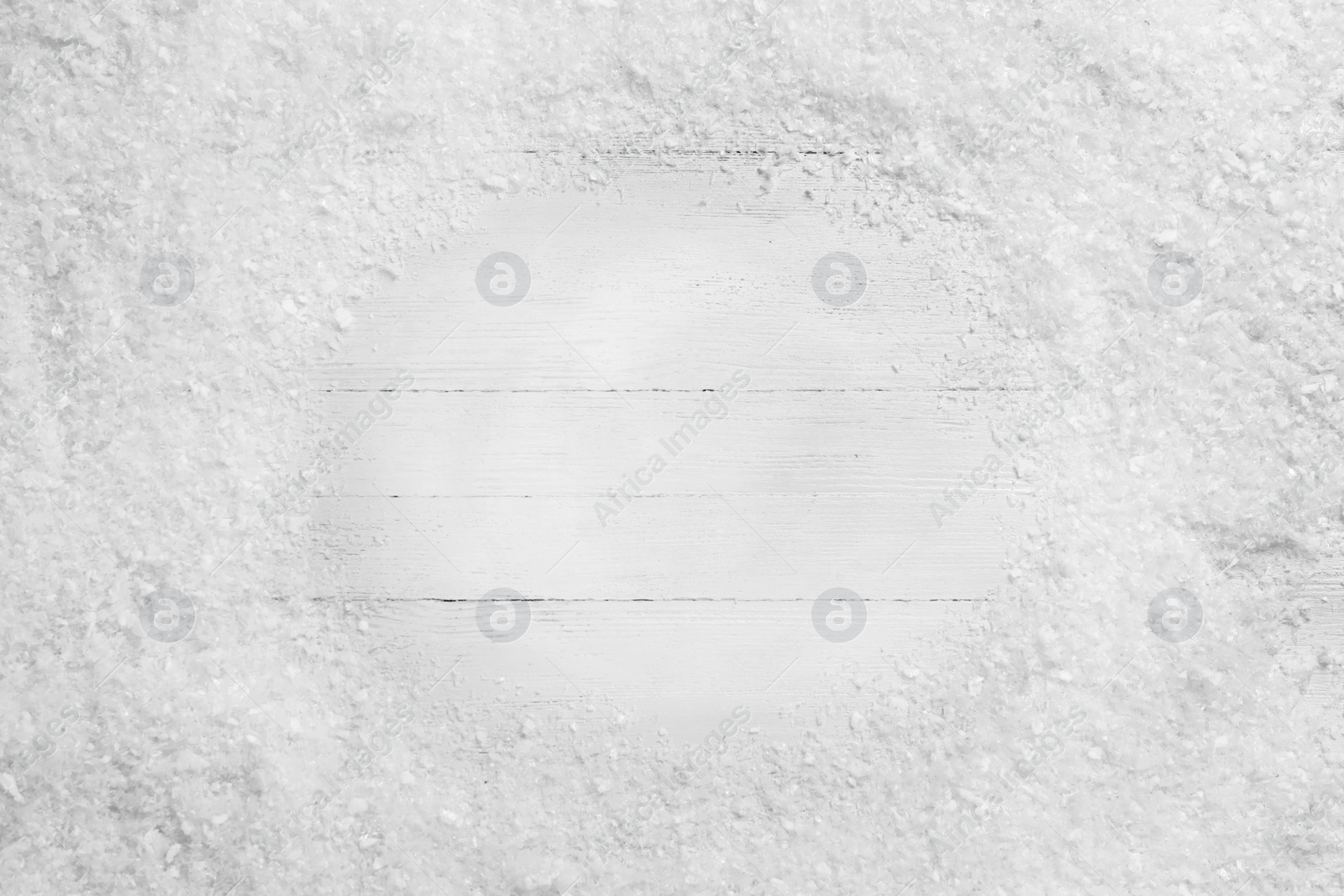 Photo of Frame of snow on white wooden background, top view with space for text. Christmas season