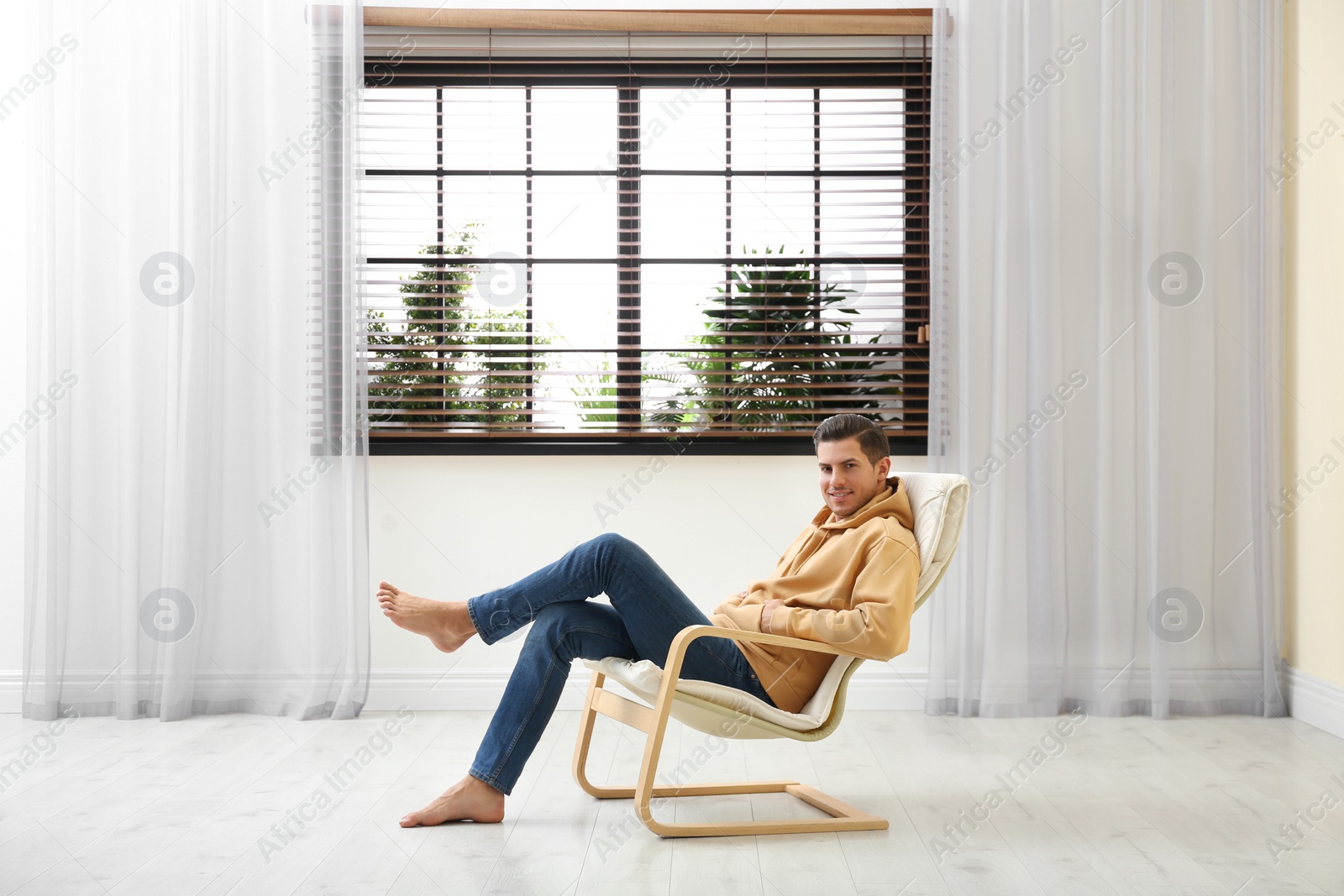 Photo of Attractive man relaxing in armchair near window at home