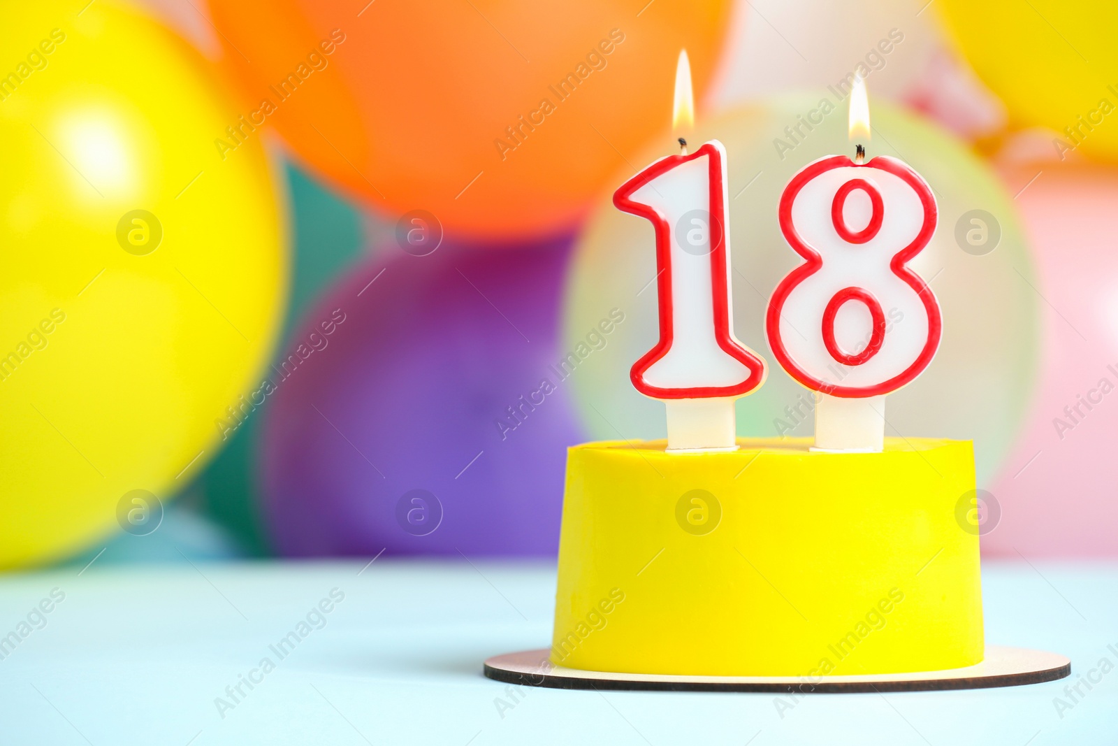 Photo of Coming of age party - 18th birthday. Delicious cake with number shaped candles on light blue table near balloons, space for text