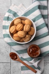 Photo of Delicious nut shaped cookies with boiled condensed milk on light textured table, flat lay