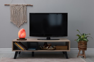 Photo of Stylish room interior with TV set, himalayan salt lamp and decor elements