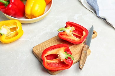 Photo of Board with cut bell peppers and knife on marble table