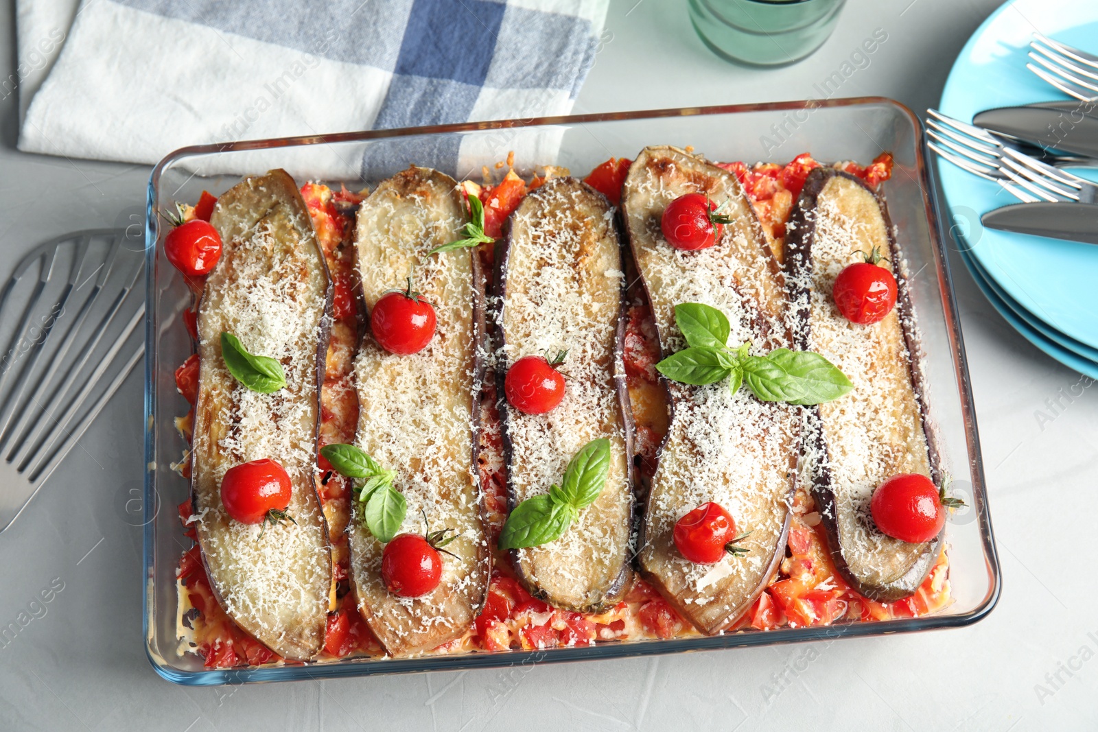 Photo of Flat lay composition with baked eggplant, tomatoes and basil in dishware on table