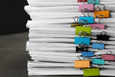 Photo of Stack of documents with binder clips on grey stone table, closeup view