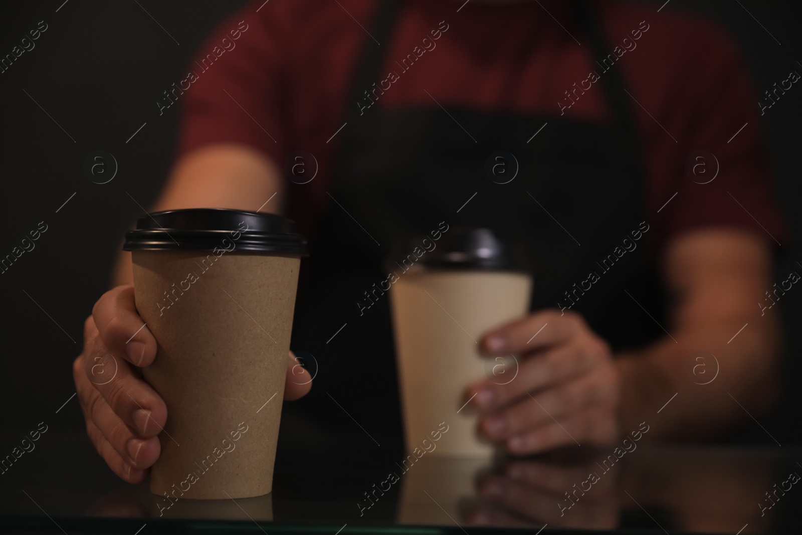 Photo of Barista putting takeaway coffee cups on glass table, closeup