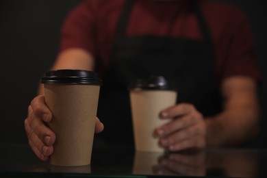 Photo of Barista putting takeaway coffee cups on glass table, closeup