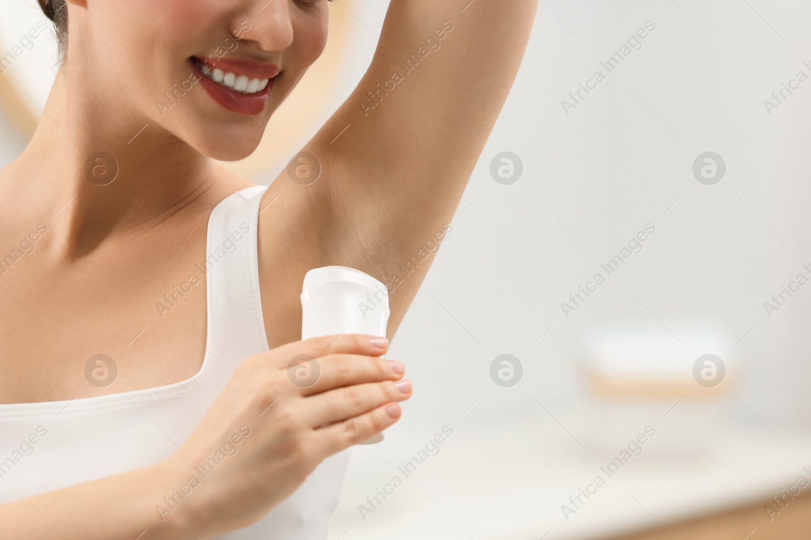 Photo of Woman applying deodorant in bathroom, closeup. Space for text