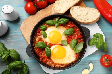 Delicious Shakshuka served on light blue wooden table, flat lay