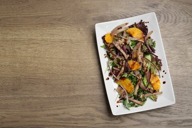 Delicious salad with beef tongue, orange and onion on wooden table, top view. Space for text