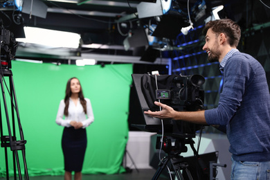 Photo of Presenter and video camera operator working in studio. News broadcasting