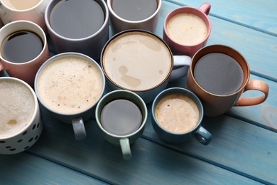 Many cups of different coffee drinks on light blue wooden table, above view