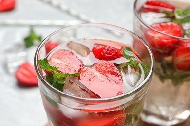 Glass of refreshing drink with strawberry and mint on table, closeup view