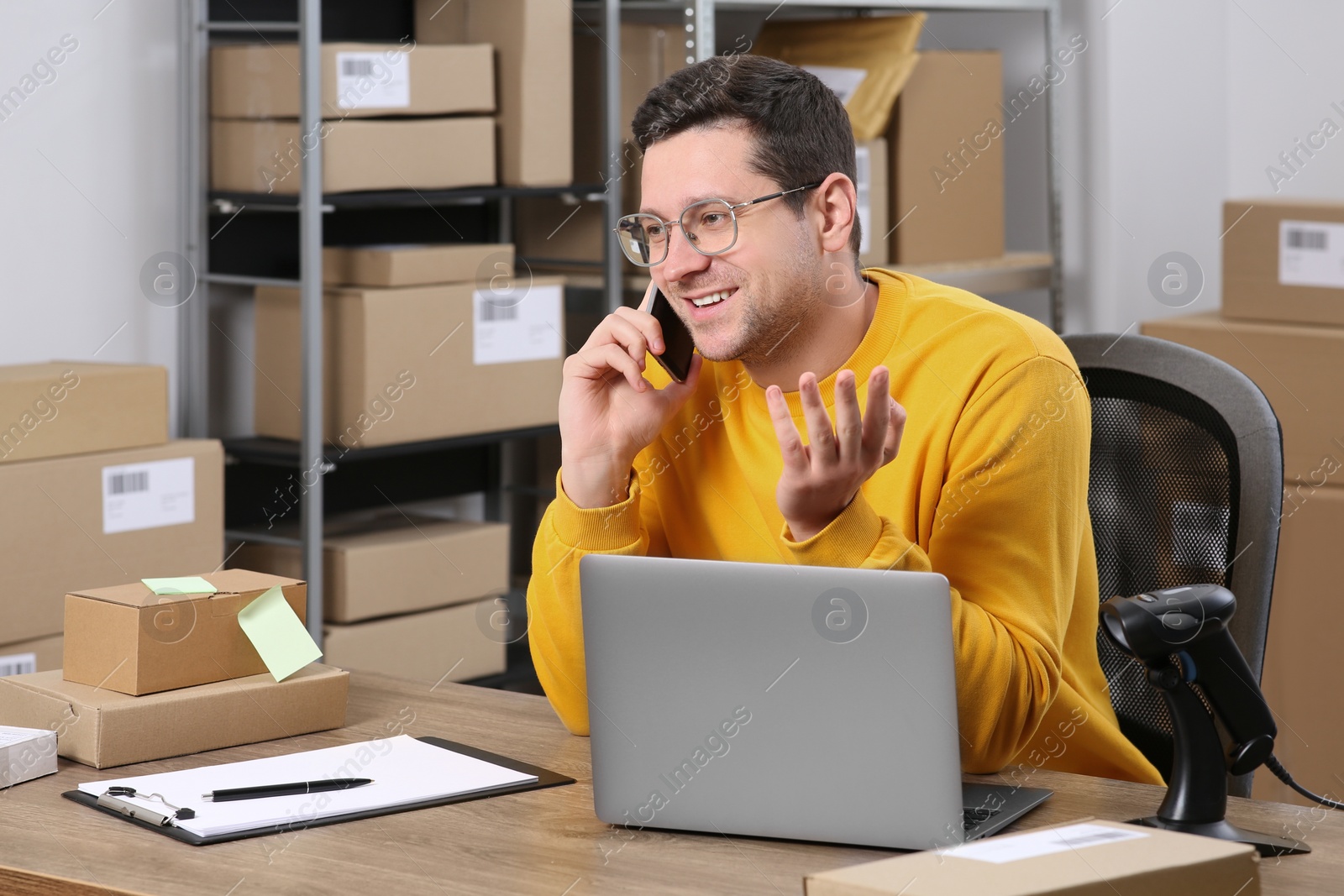 Photo of Seller talking on phone while working in office. Online store