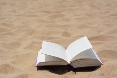 Photo of Open book on sandy beach, space for text