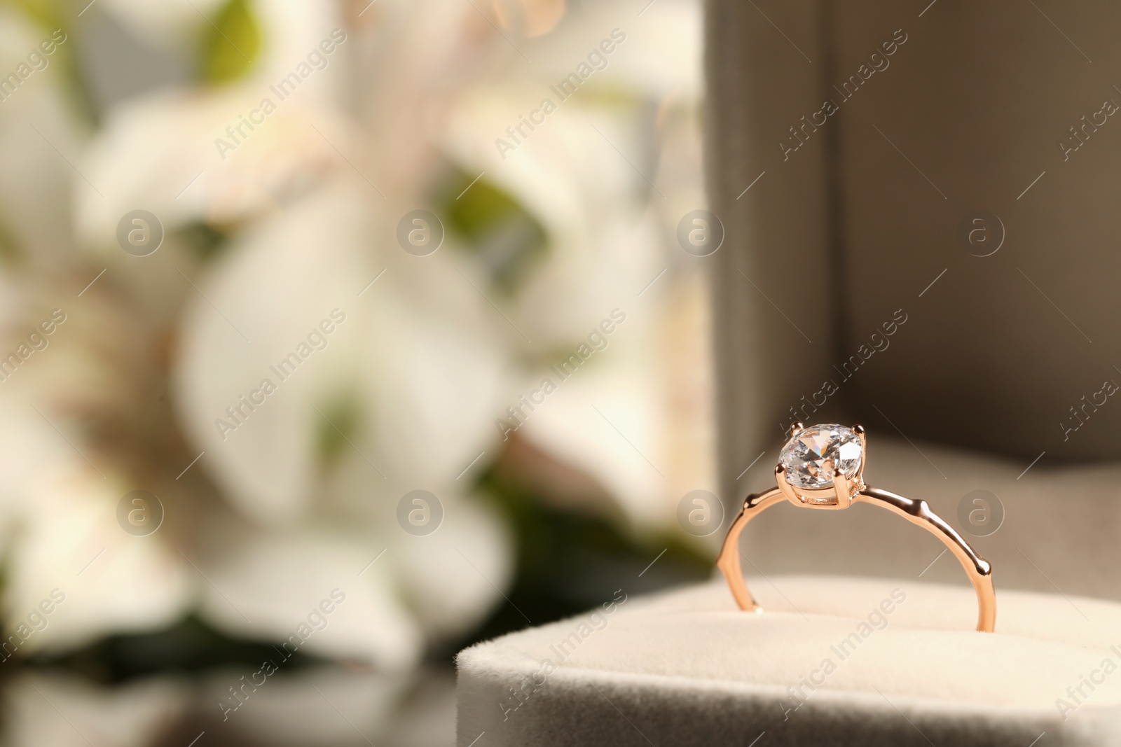 Photo of Beautiful engagement ring in box against blurred background, closeup. Space for text