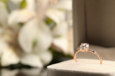 Photo of Beautiful engagement ring in box against blurred background, closeup. Space for text