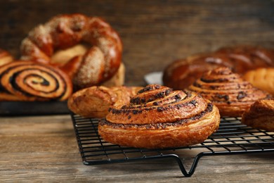 Photo of Freshly baked spiral bun and other pastries on wooden table, closeup