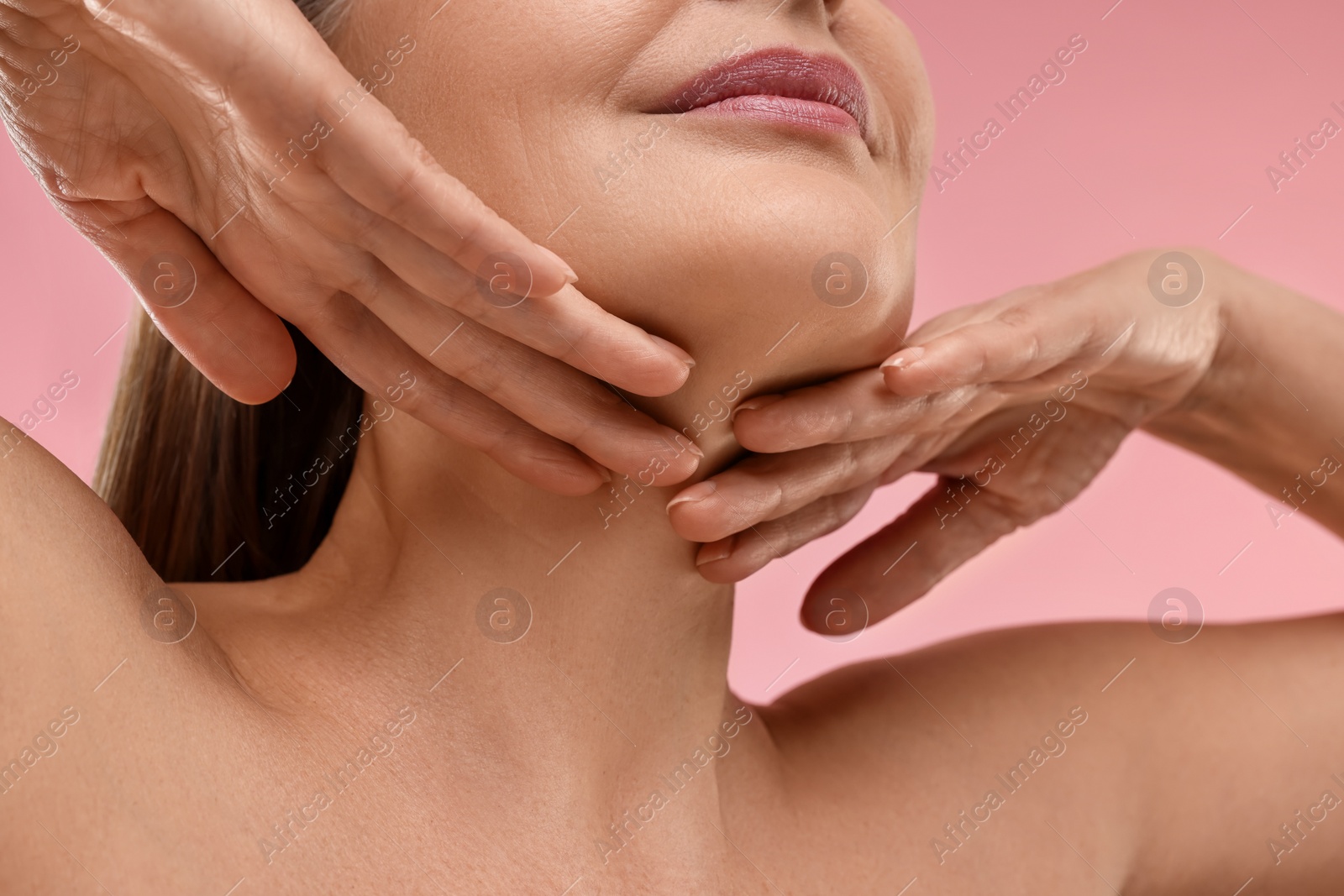 Photo of Mature woman touching her neck on pink background, low angle view