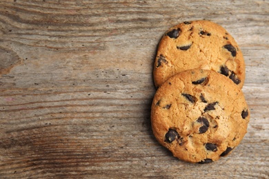 Photo of Delicious chocolate chip cookies on wooden table, flat lay. Space for text