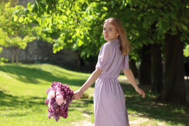 Beautiful woman with bouquet of spring flowers in park on sunny day